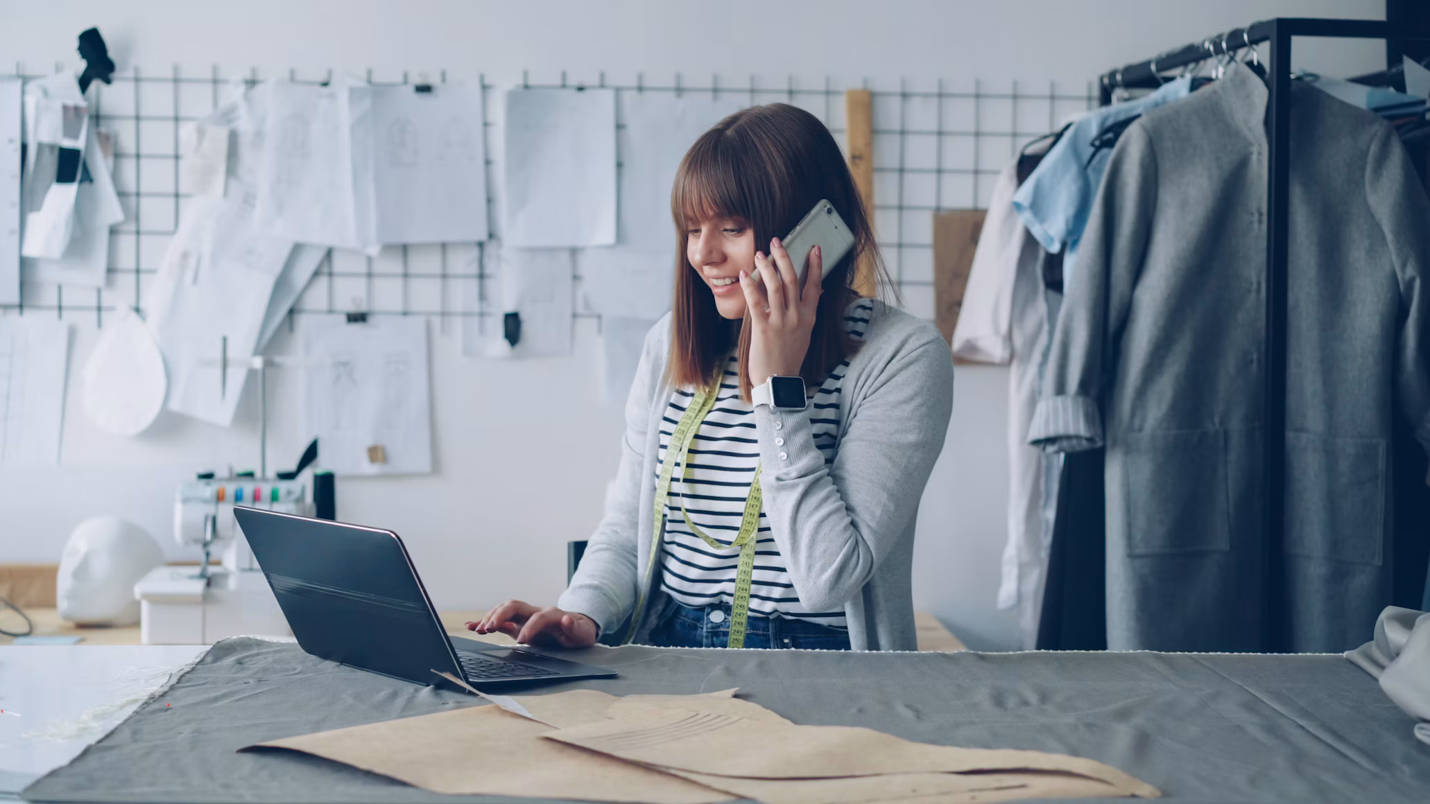A small business owner answering a customer on her phone while working at her laptop